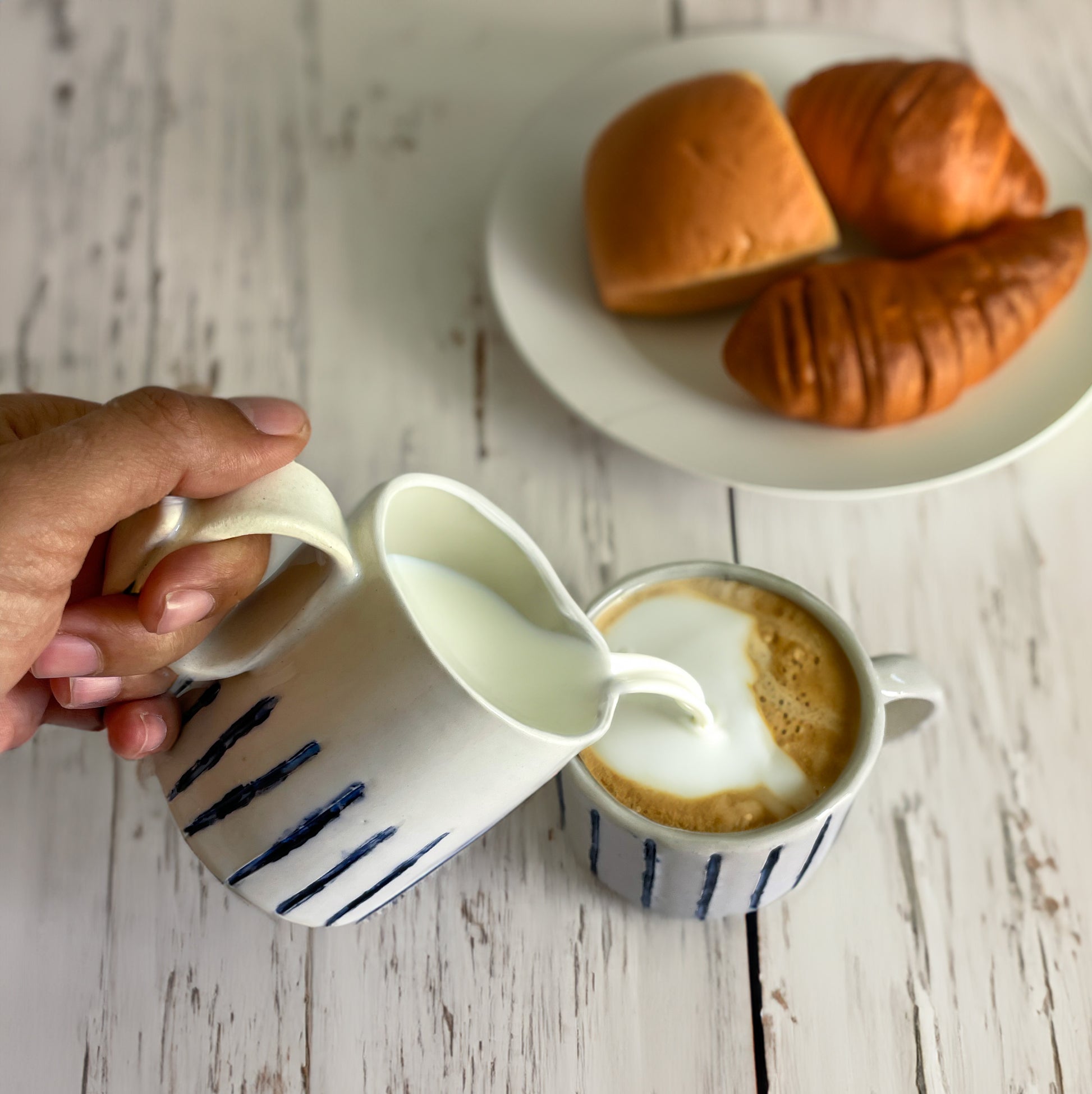 pouring milk over a cup of coffee